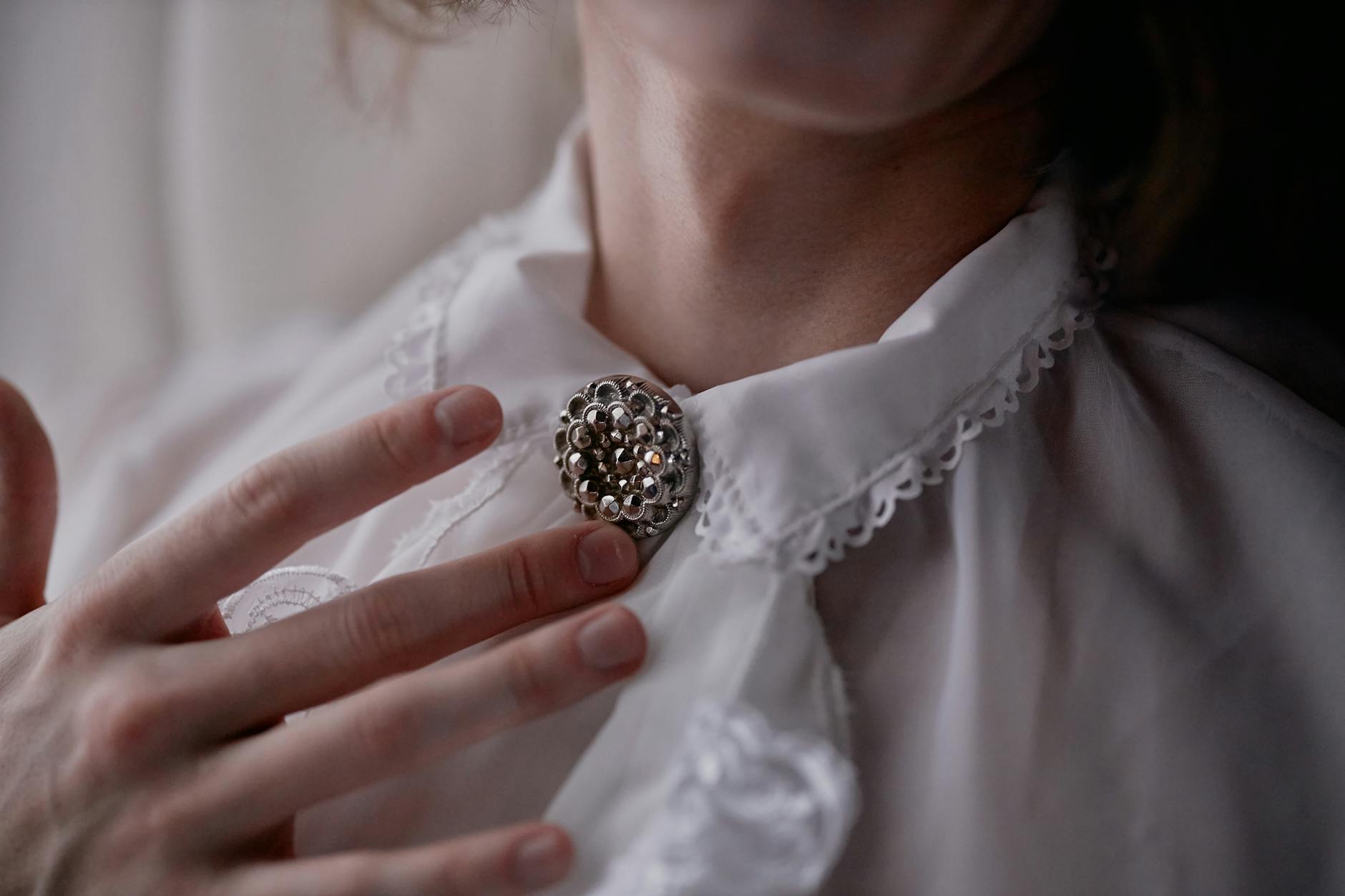 hand touching vintage brooch pinned to collar